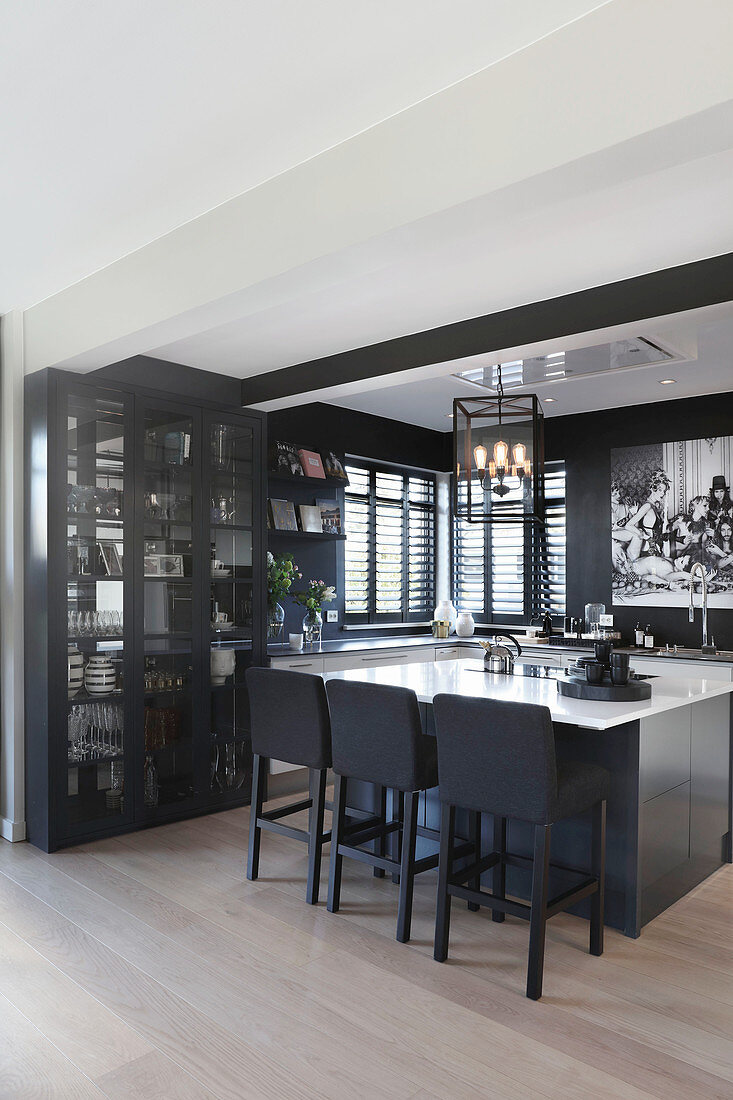 Elegante, offene Küche mit Vitrinenschrank, Kücheninsel und schwarzen Wänden