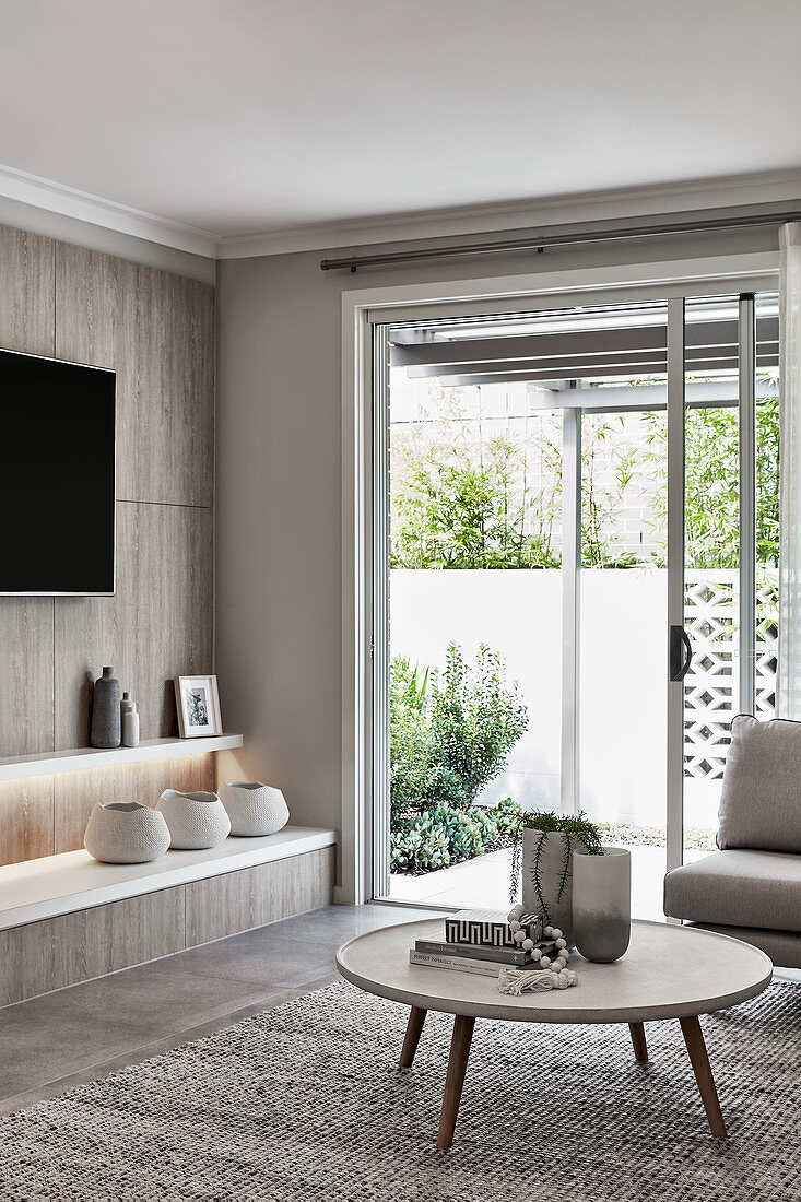 Coffeetable, Wandregale und Fernseher im Wohnzimmer mit Terrassentür