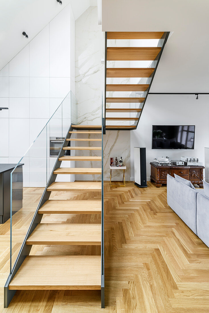 Treppenaufgang mit Glasgeländer als Raumteiler in offenem Wohnraum