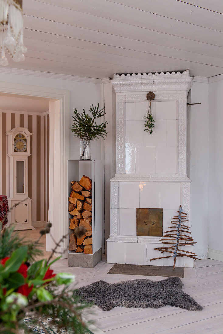White tiled stove and stacked firewood in living room