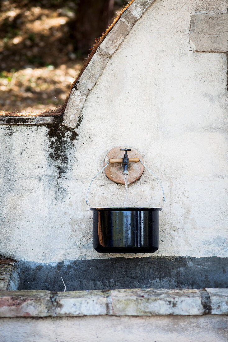 Kochtopf mit Wasser am Steinbrunnen