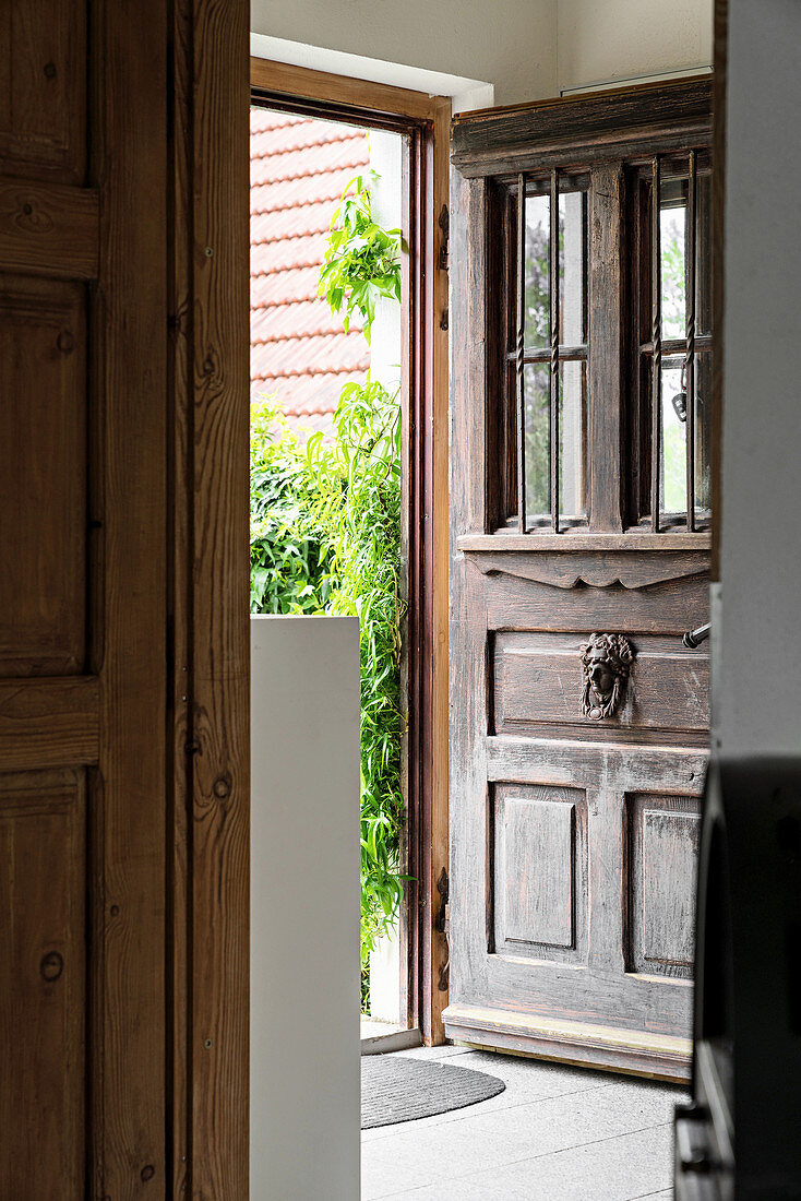 Geöffnete Eingangtür aus Holz mit klassischem Metall-Türklopfer