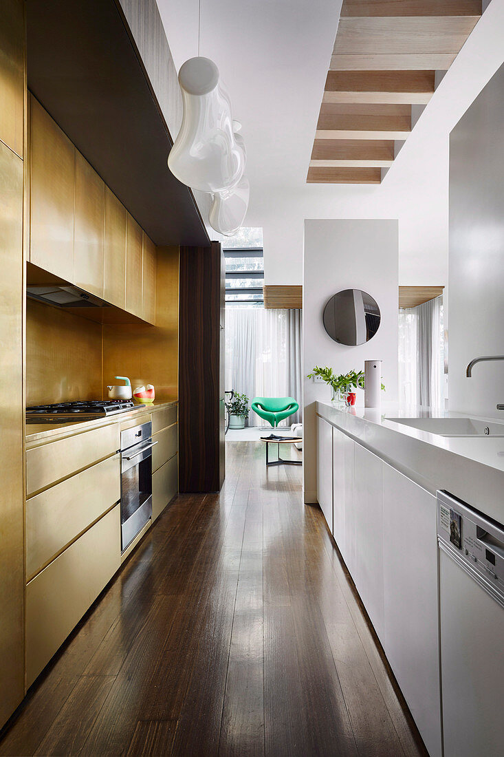 Elongated kitchen with white and gold-colored kitchen units