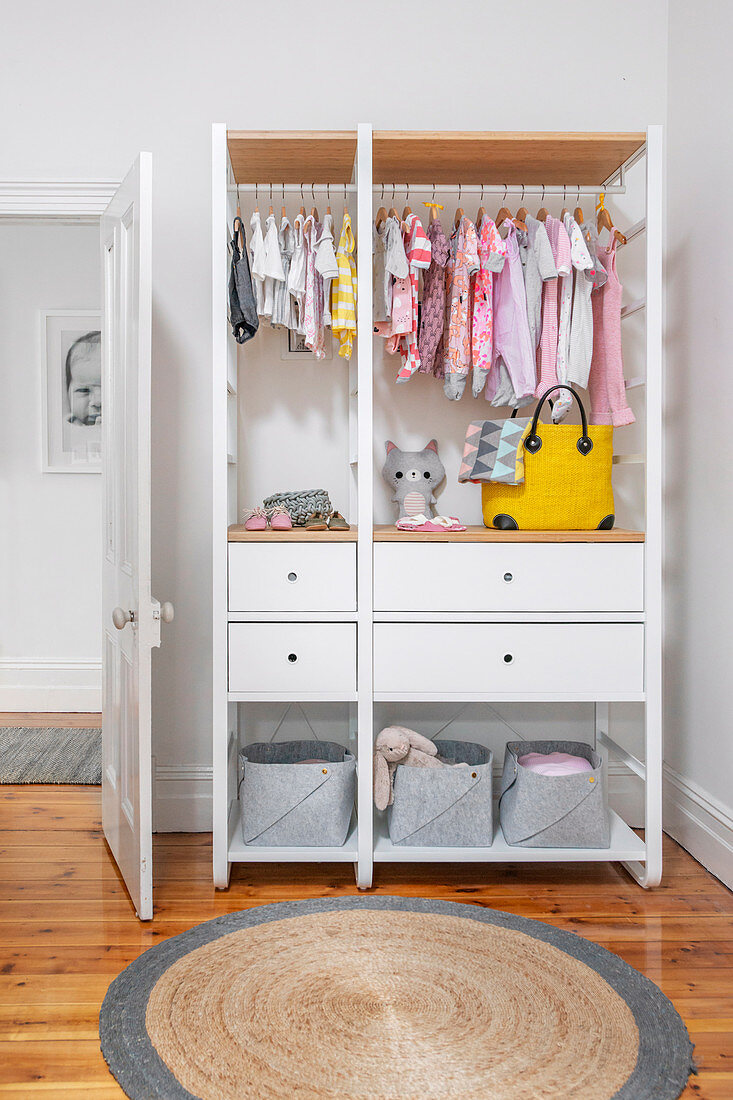 Weißer offener Kleiderschrank mit Babykleidung in Kinderzimmer