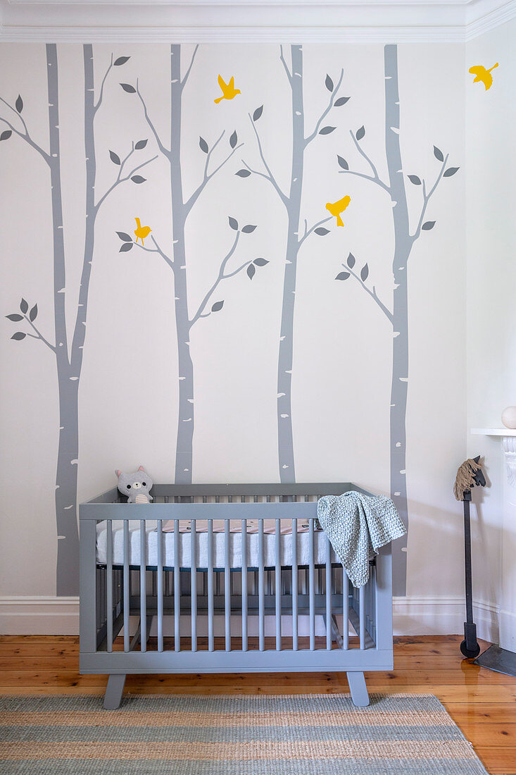 Blue crib in baby room with cheerful wall painting