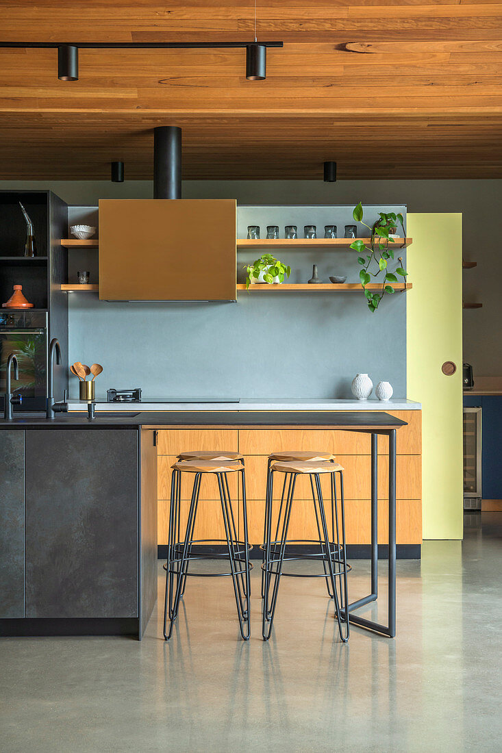 Offener Küchenbereich mit hellblauer Küchenrückwand und anthrazitfarbener Frühstückstheke