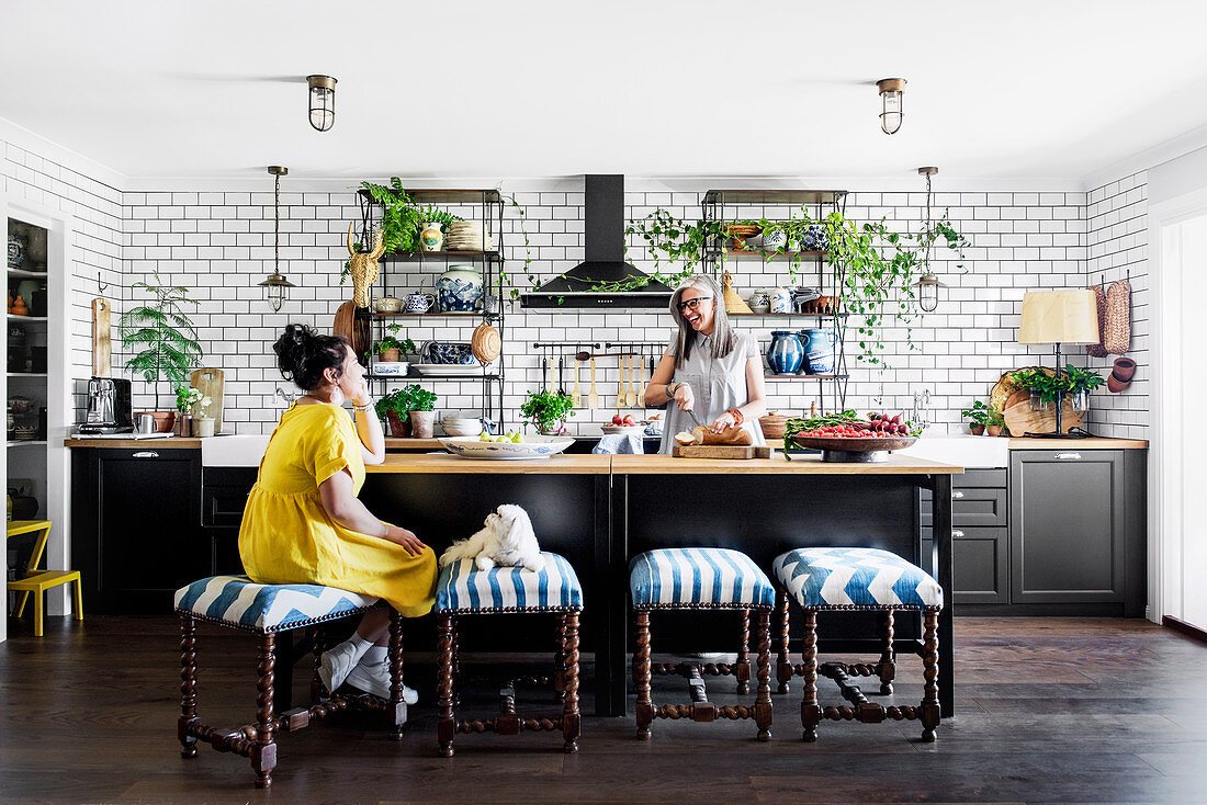 Küche mit Metrofliesenwand und gedrechselten Polsterhockern vor Kücheninsel