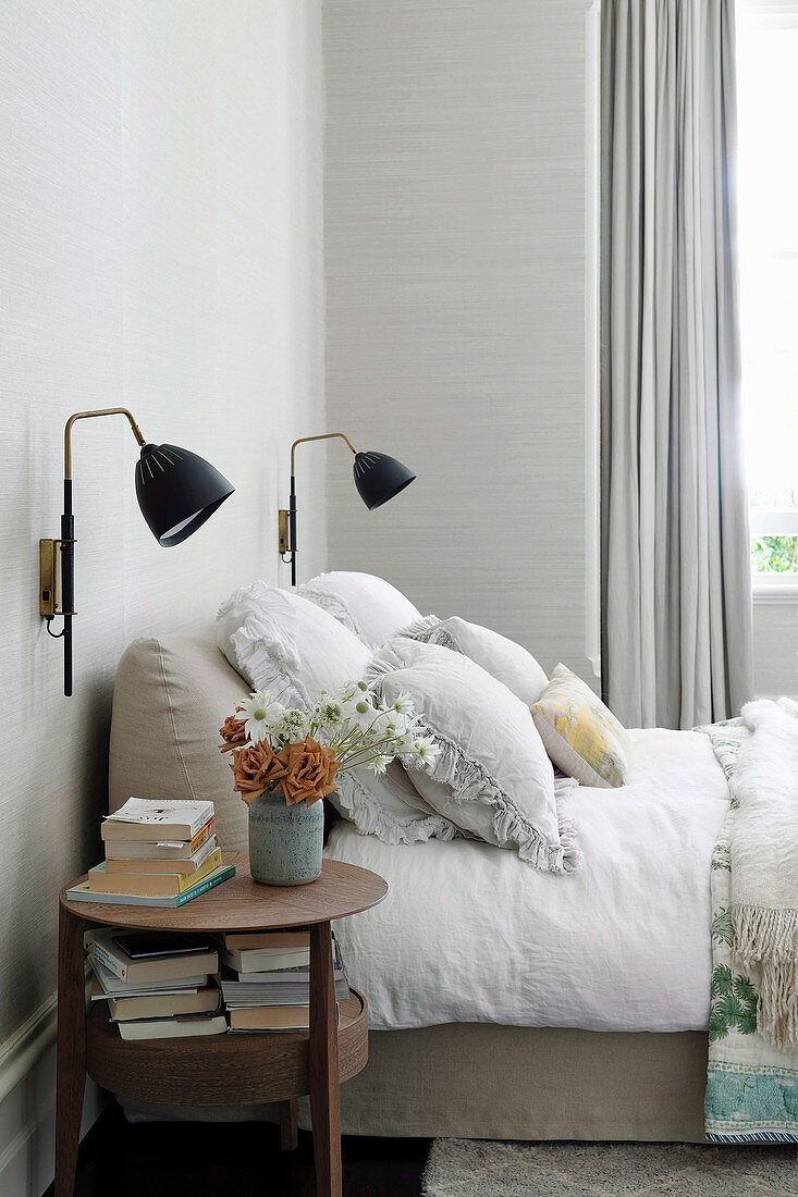 Round side table next to a cozy beige upholstered bed