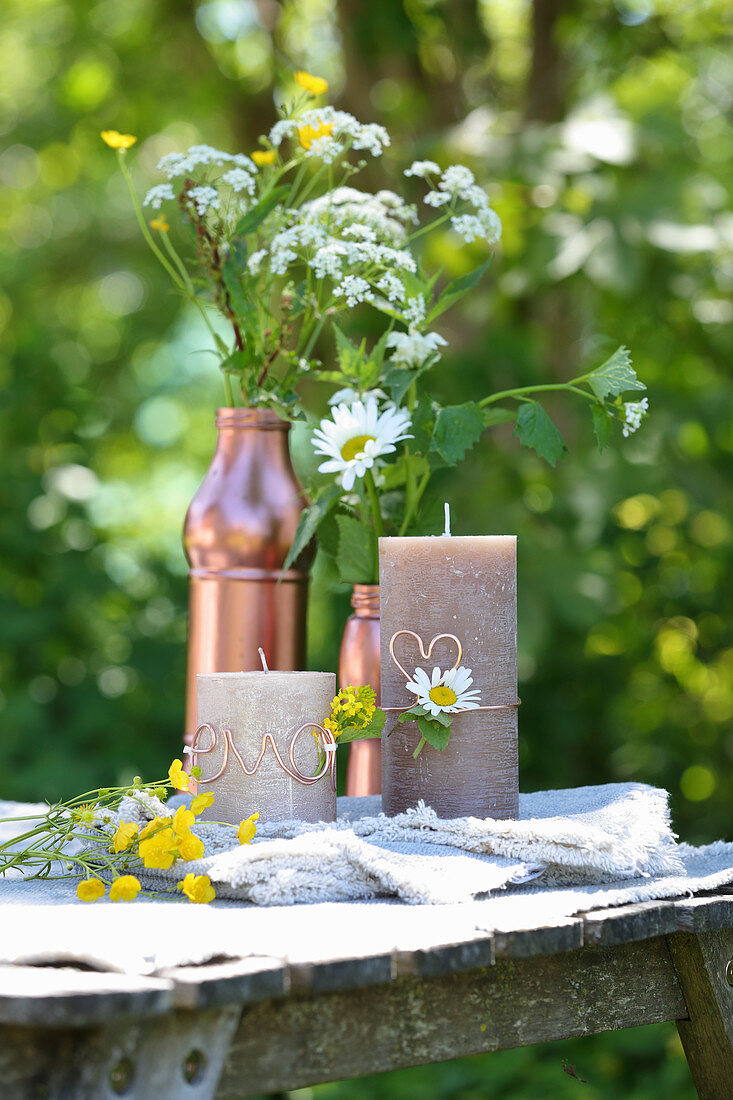 Wildflowers in copper-coloured containers and candles decorated with copper wire