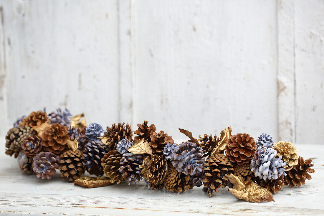 Winter arrangement of leaves and pine cones dipped in coloured wax or sprayed gold