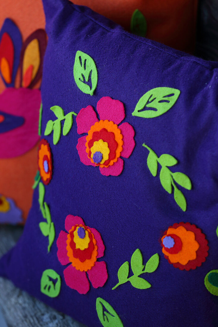 Farbenfrohe Zierkissen folkloristisch dekoriert mit Filzblüten und Filzblättern