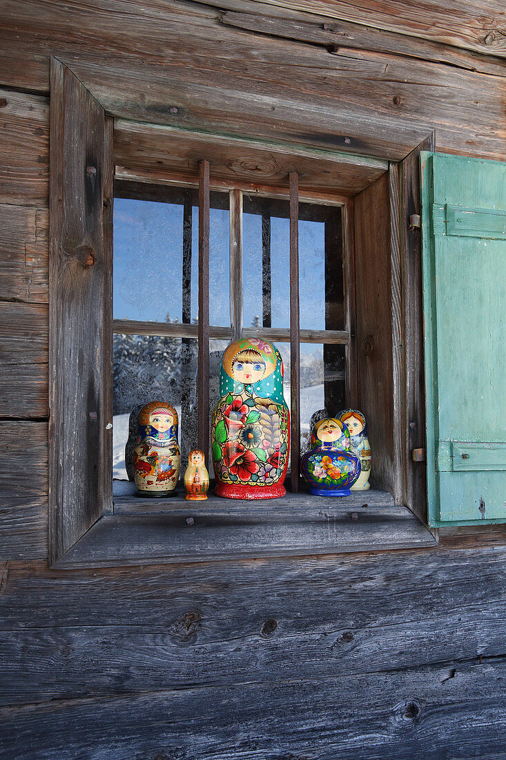 Traditionelle Matrjoschka auf Fenstersims einer Holzhütte