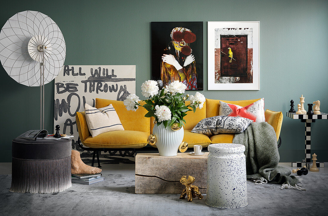 Wohnzimmer mit Kunstobjekten und gelbem Sofa vor grauer Wand