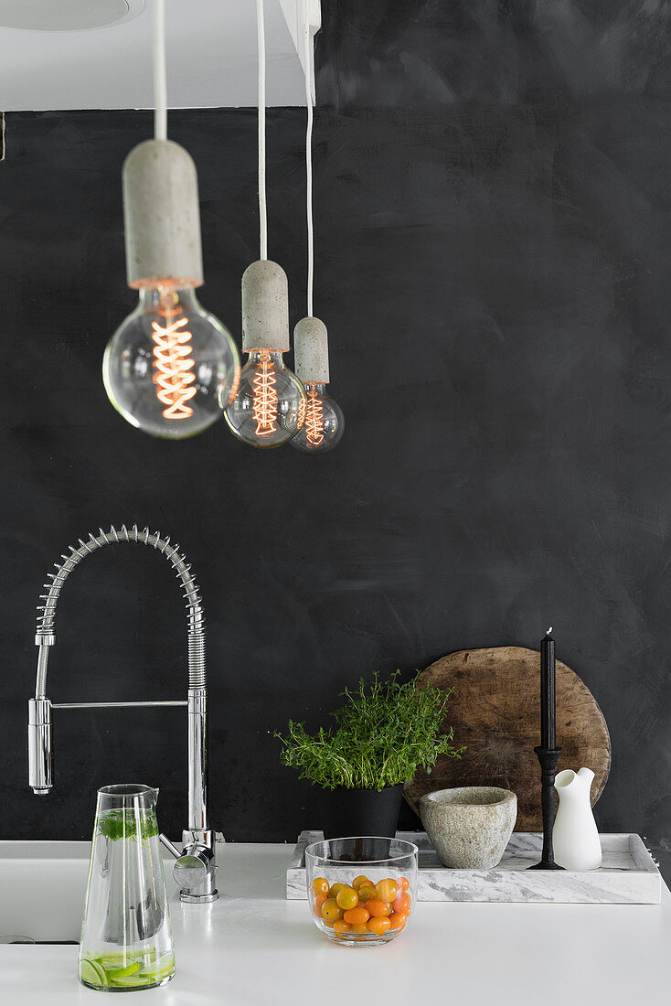 Küchenarbeitsplatte vor anthrazitfarbener Wand mit hängenden Glühlampen