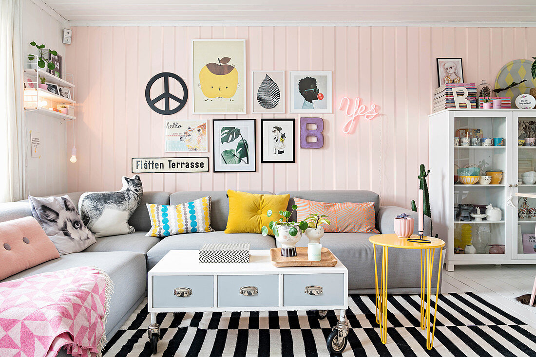 Grey corner sofa with scatter cushions in living room with pink wooden wall
