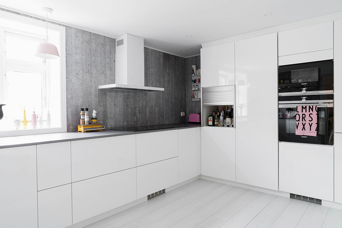 Simple white kitchen with grey worksurfaces and grey back wall