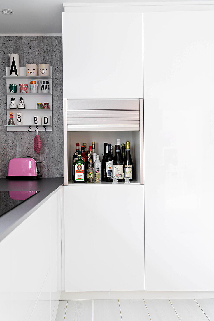 Simple white kitchen with miniature bar in roller-fronted cupboard