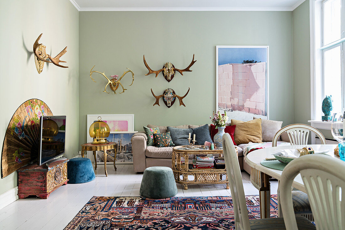 Antlers on pastel-green walls of Bohemian-style living room