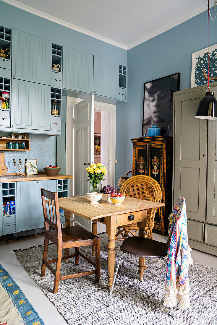 Pale blue cupboards and rustic wooden dining table in Bohemian-style kitchen