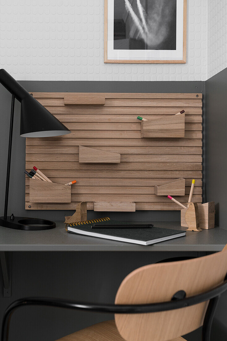 Desk area with storage boxes for writing utensils on wooden panel