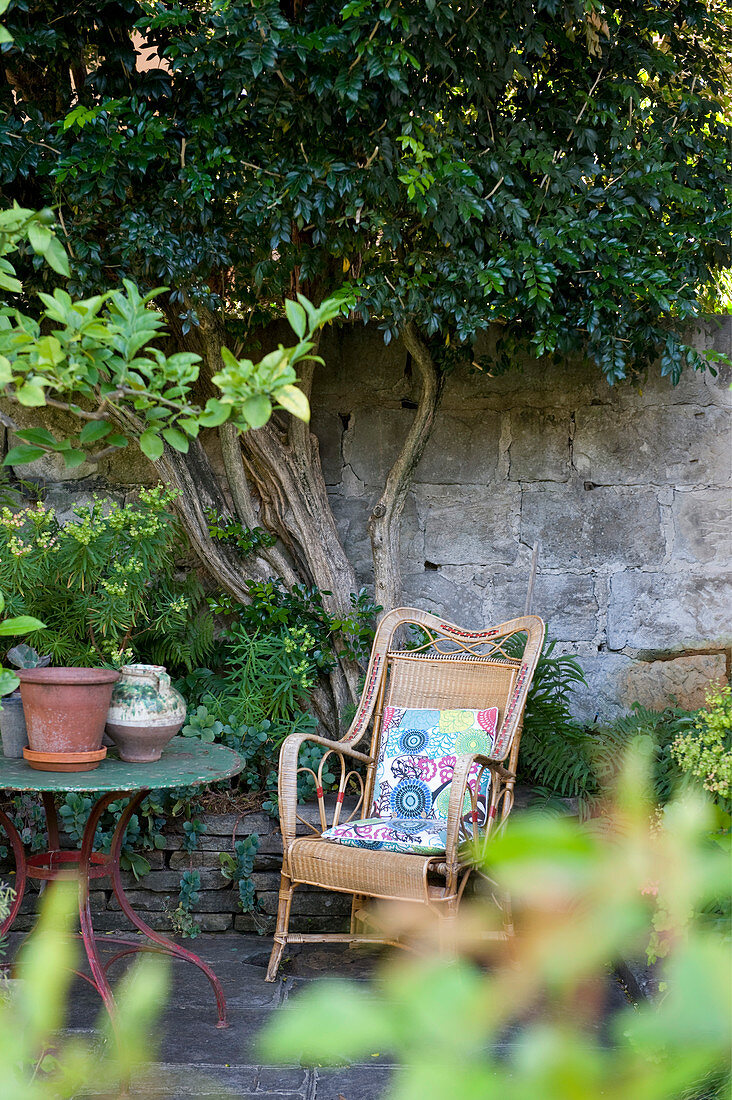 Rattan armchair against stone wall in Mediterranean garden