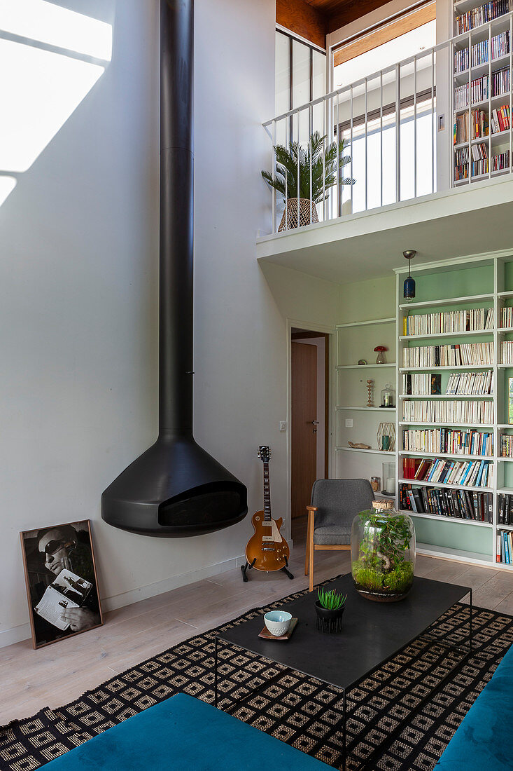 Suspended fireplace with double-height stove pipe in maisonette apartment