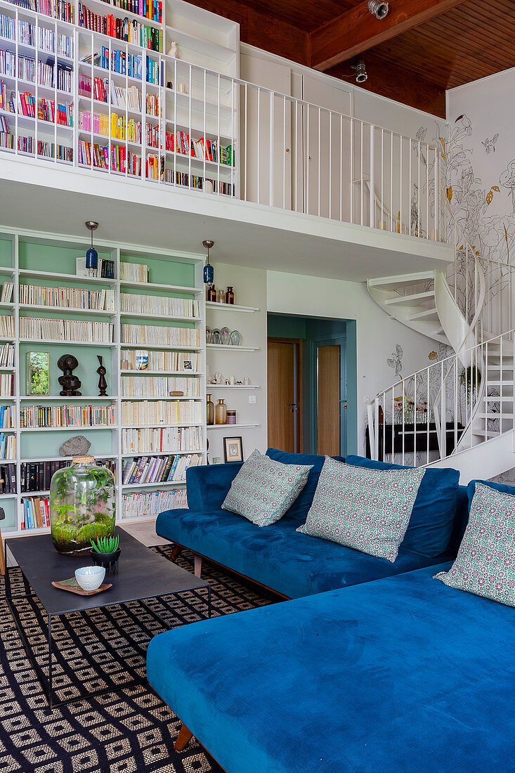 Blue velvet modular sofa in maisonette apartment with white winding staircase and gallery