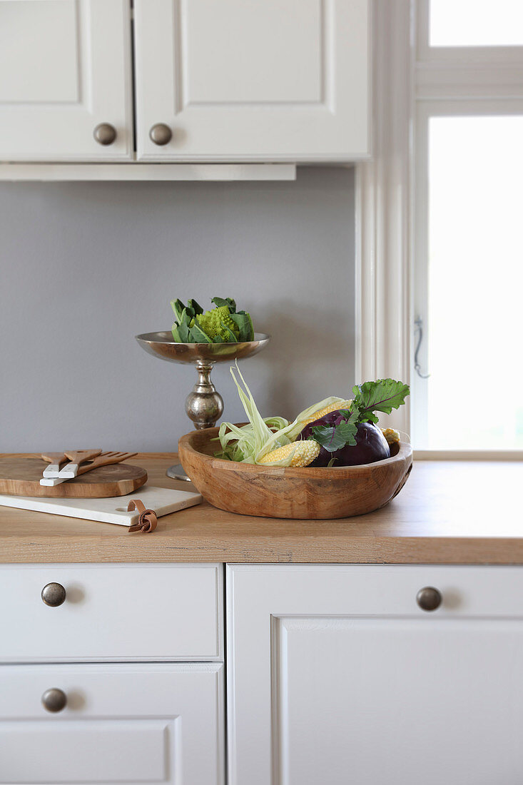 Rustikale Holzschale und silberne Etagere mit Gemüse in der Küche