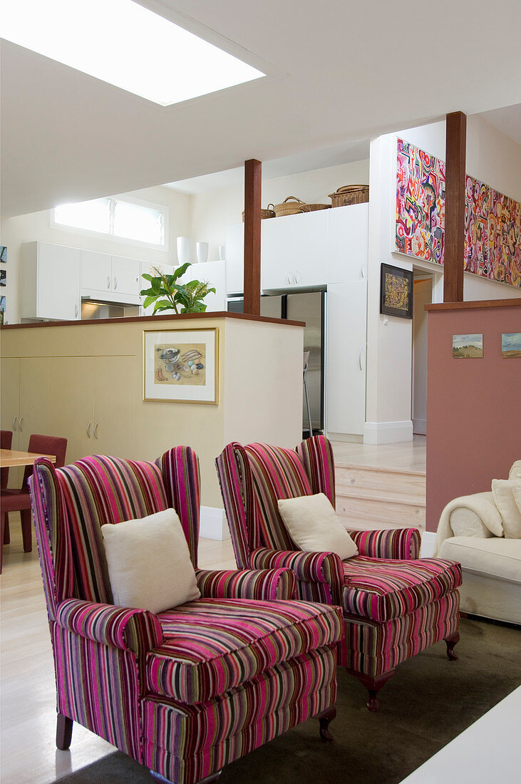 Pink striped armchairs in open-plan, split-level interior