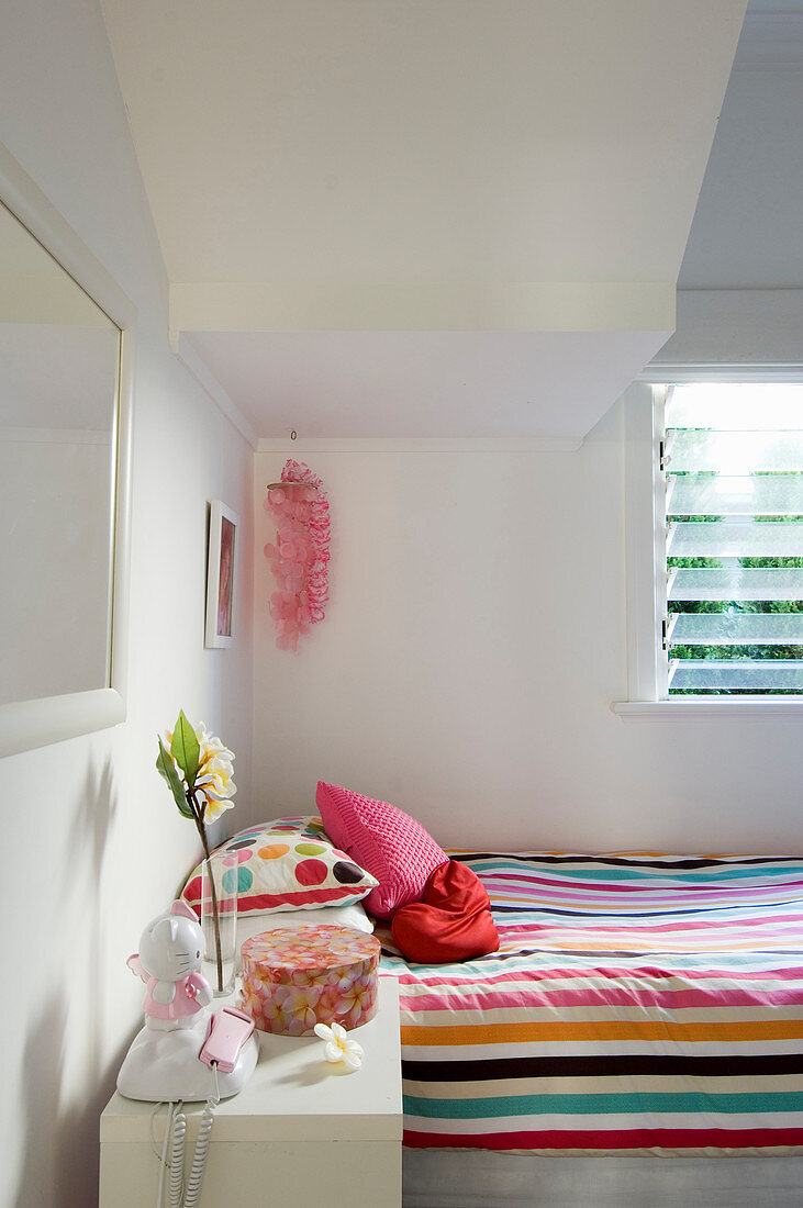 Light-flooded, white bedroom with colourful bed linen