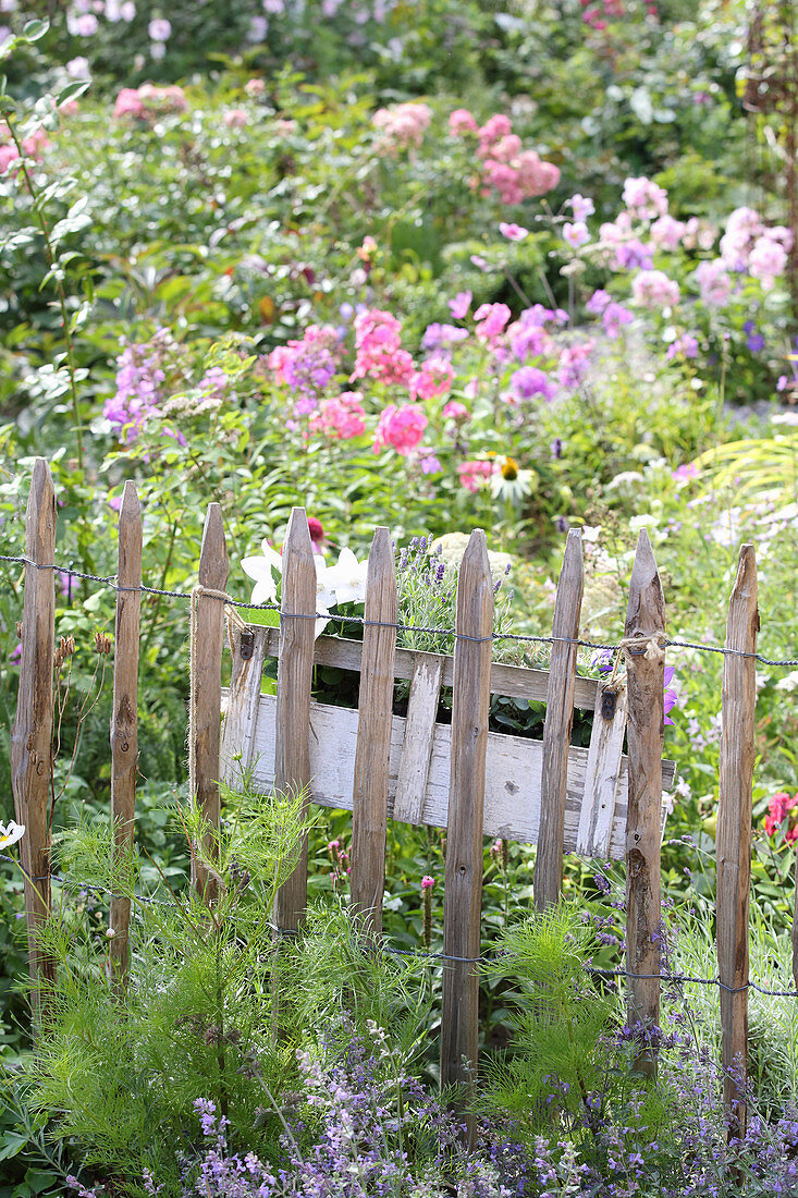 Blumenkasten am Staketenzaun im blühenden Garten