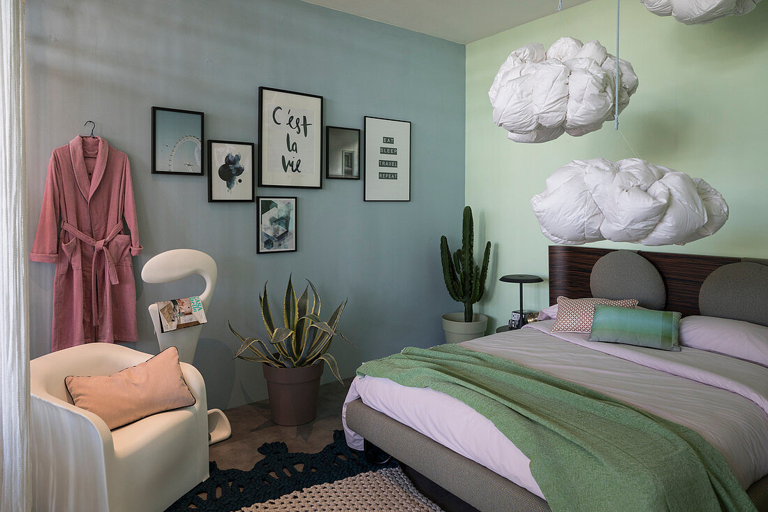 Schlafzimmer mit verschiedenfarbigen Wänden und aufgehängten Federkissen als Wolkendeko