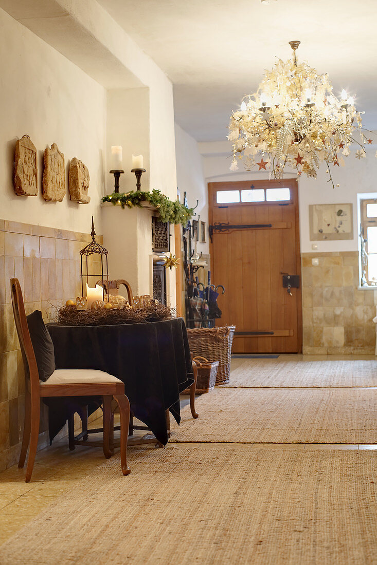 Brown tablecloth and Advent wreath on round table and chandelier with opulent Christmas decorations in rustic hallway