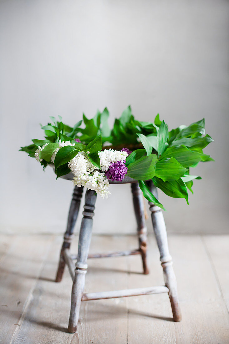 Wreath of lilac and lily-of-the-valley leaves on stool
