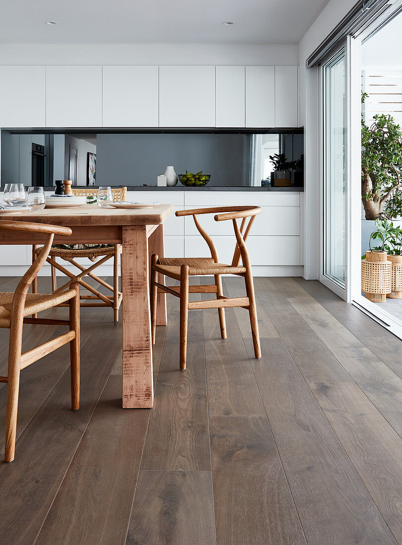 Designer chairs around rustic wooden table in modern kitchen