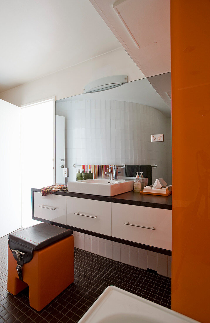 Waschtisch und Aufsatzbecken in hellem Badezimmer mit orangefarbenen Akzenten