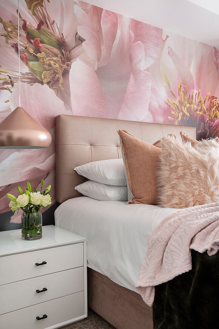 Doppelbett mit Bettkopfende, Nachtkästchen, darüber Pendelleuchte und Tapete mit Blumenmotiv im Schlafzimmer
