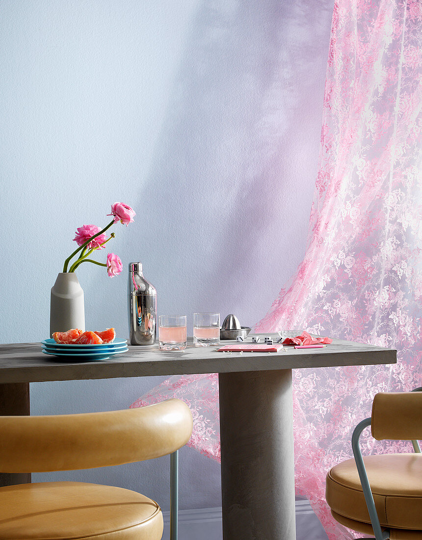 Esstisch aus Beton, Lederstühle und rosa Vorhang