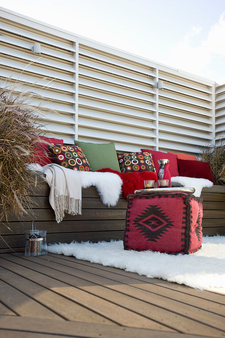 Cubic pouffe in front of bench with cushions on comfortable terrace
