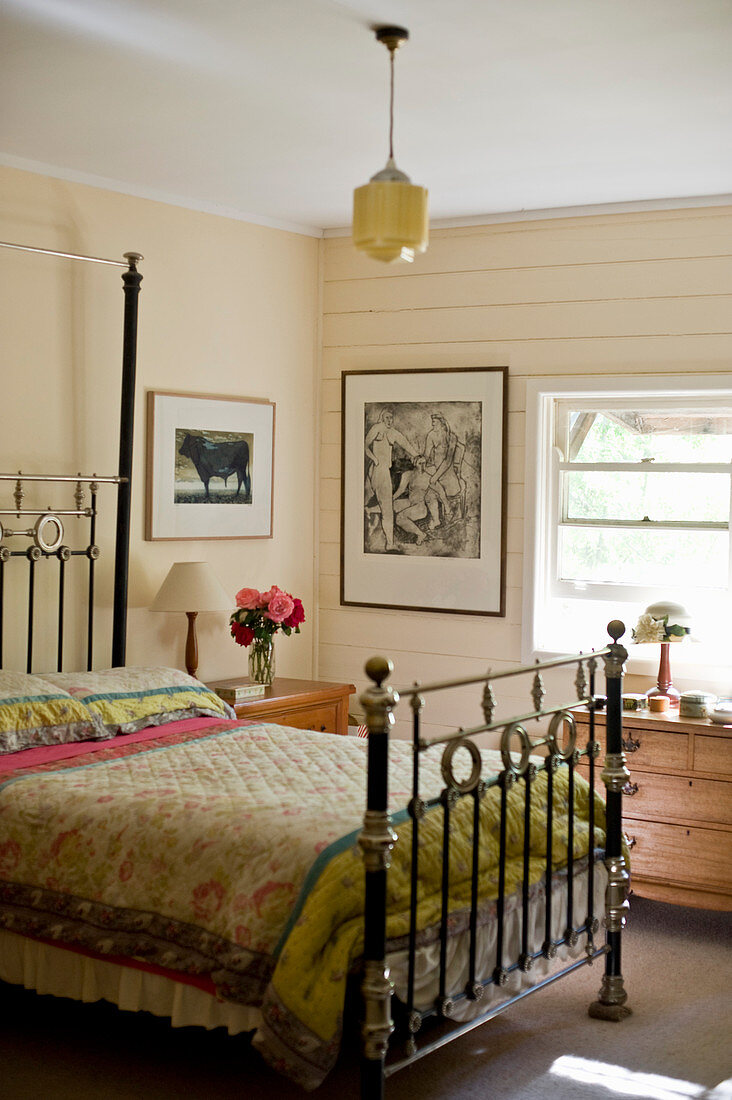 Antique double bed in bedroom with cream walls