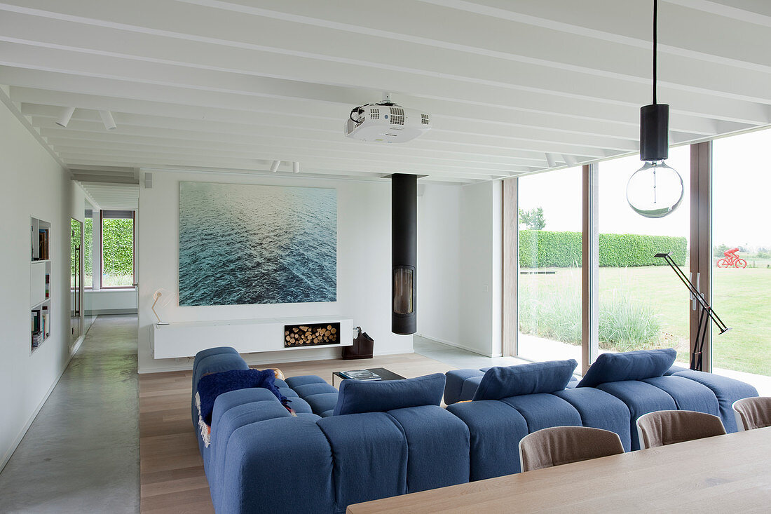 Modernes Wohnzimmer mit Fensterfront und blauem Sofa