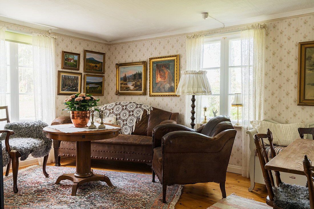 Nostalgisches Wohnzimmer mit Gemäldesammlung über braunem Ledersofa