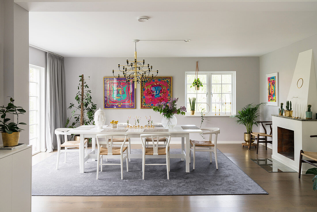 Designerstühle am weißen Tisch im eleganten Esszimmer mit Kamin