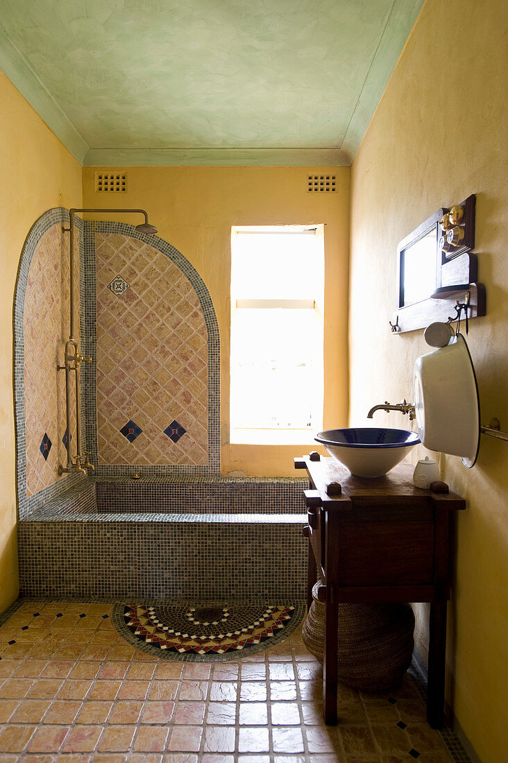 Badewanne mit Mosaikfliesen in orientalischem Badezimmer mit gelben Wänden