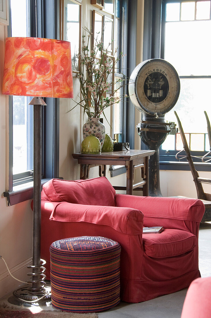 Roter Sessel, Sitzpouf und Stehleuchte, im Hintergrund Konsolentisch und Vintage Waage
