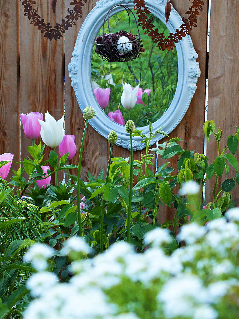 Nostalgischer Spiegel und hängende Rostherzen, davor Tulpenbeet
