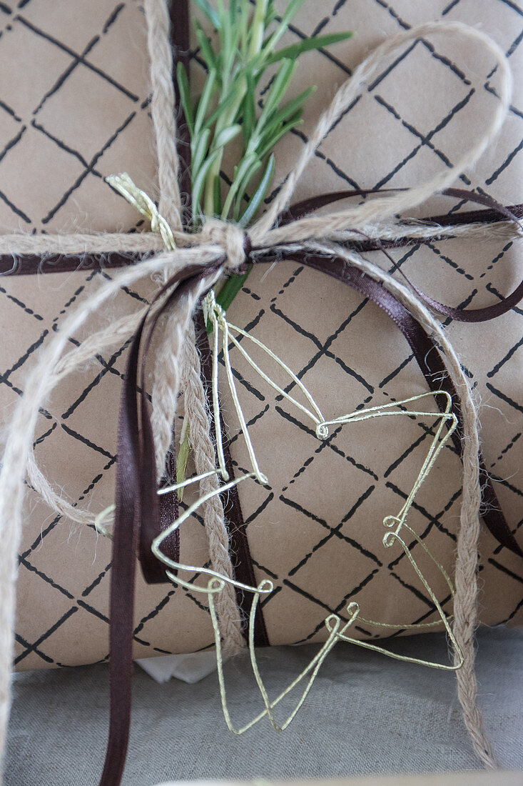 Christmas present decorated with ribbons, rosemary and delicate wire star