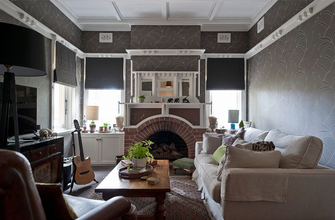 Sofa, coffee table and fireplace in traditional living room with dark wallpaper
