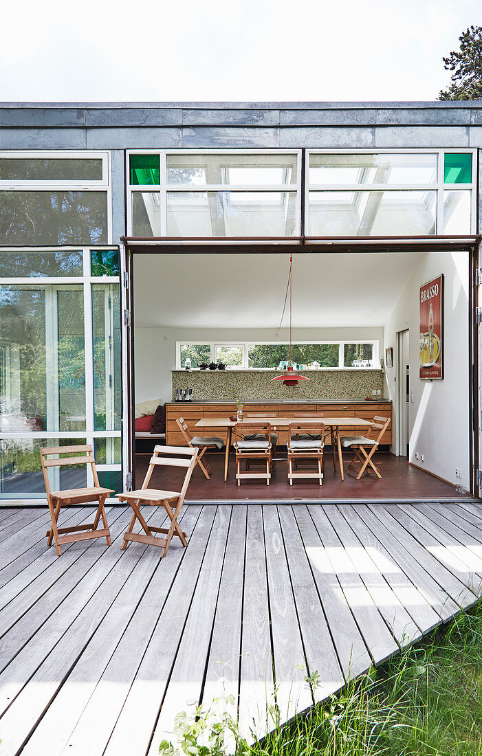 Wooden deck outside architect-designed house with large, open, glass sliding doors