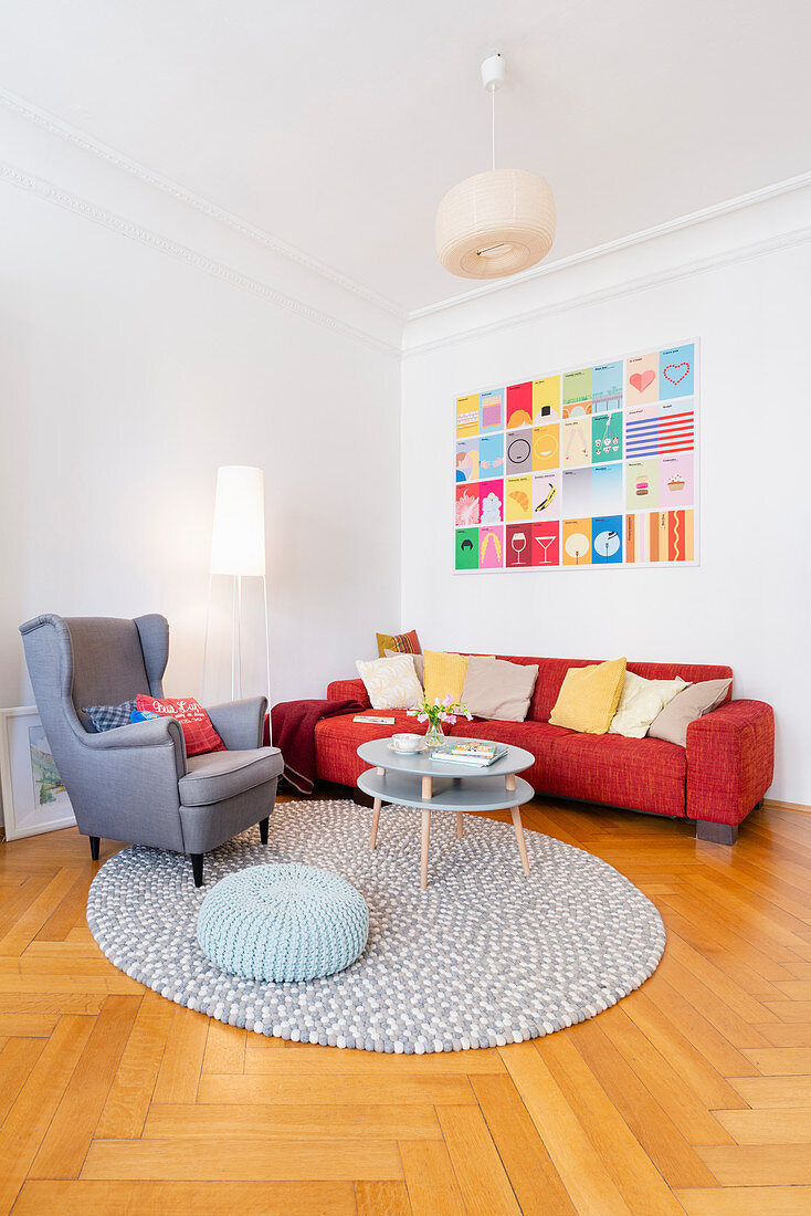 Rotes Sofa mit Kissen, Ohrensessel und Coffeetable im Wohnzimmer